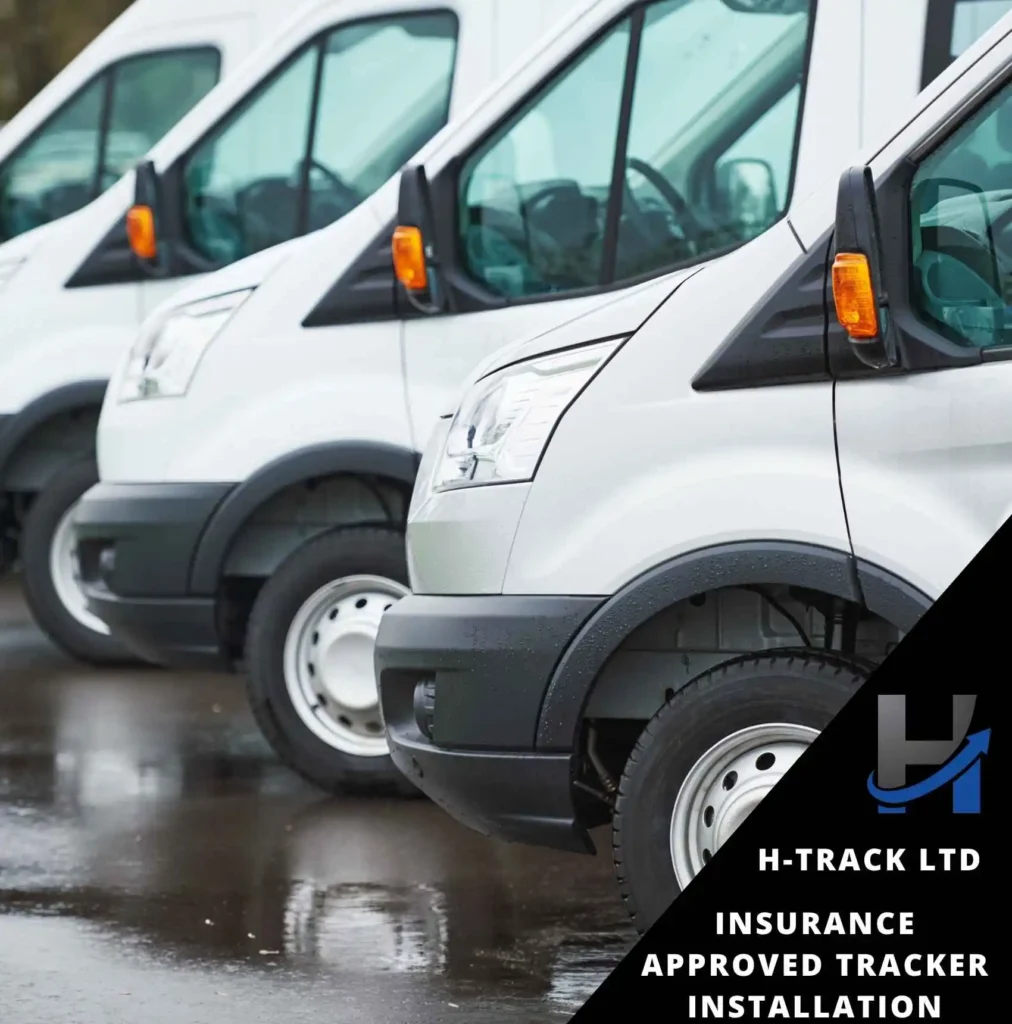 A row of white vans parked on a wet ground each having an Insurance Approved Tracker Installation by H-Track Ltd