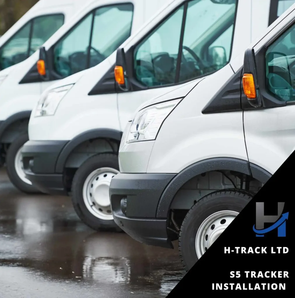A row of white vans parked on a wet ground each having an S5 Tracker Installation by H-Track Ltd